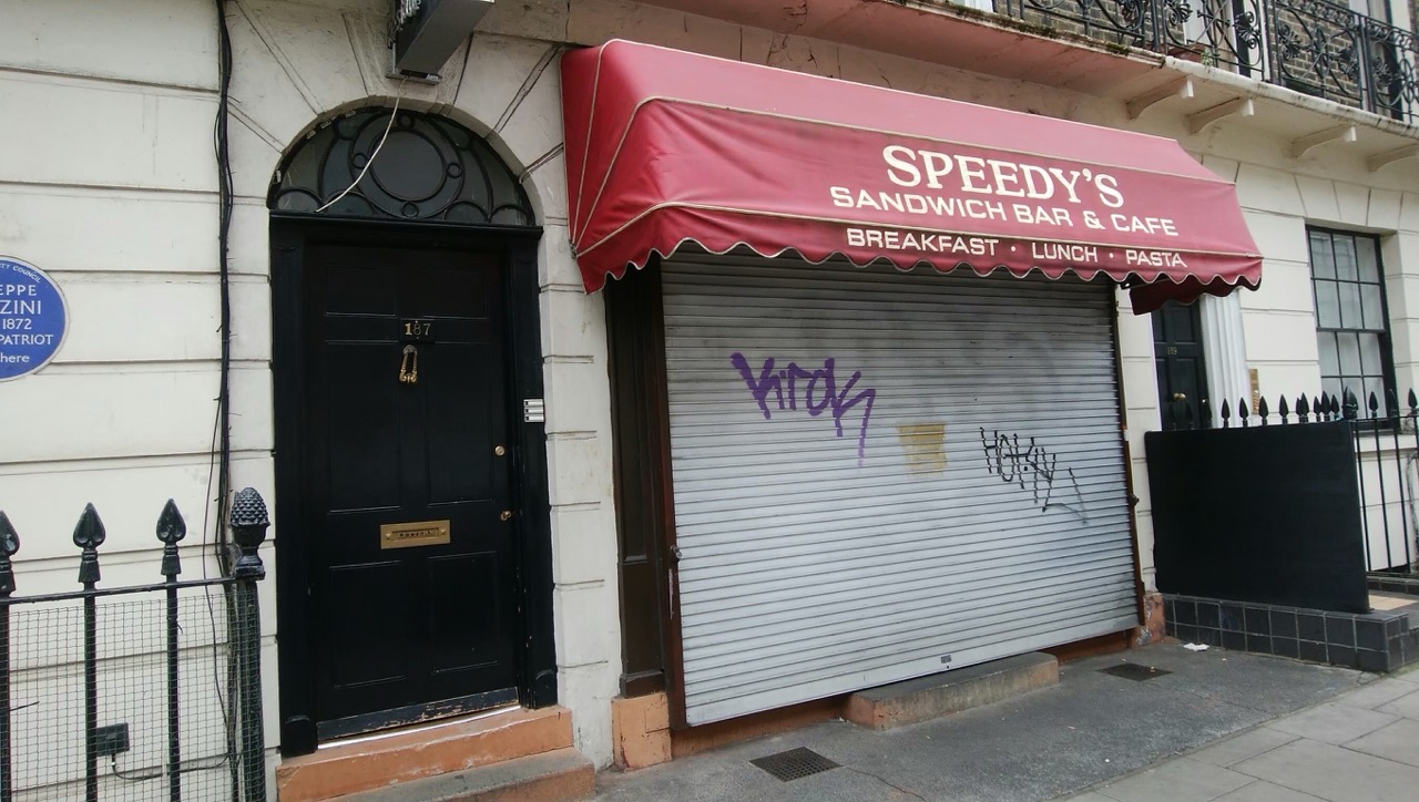 Speedy's Cafe の黒い玄関扉と赤いオーニング
