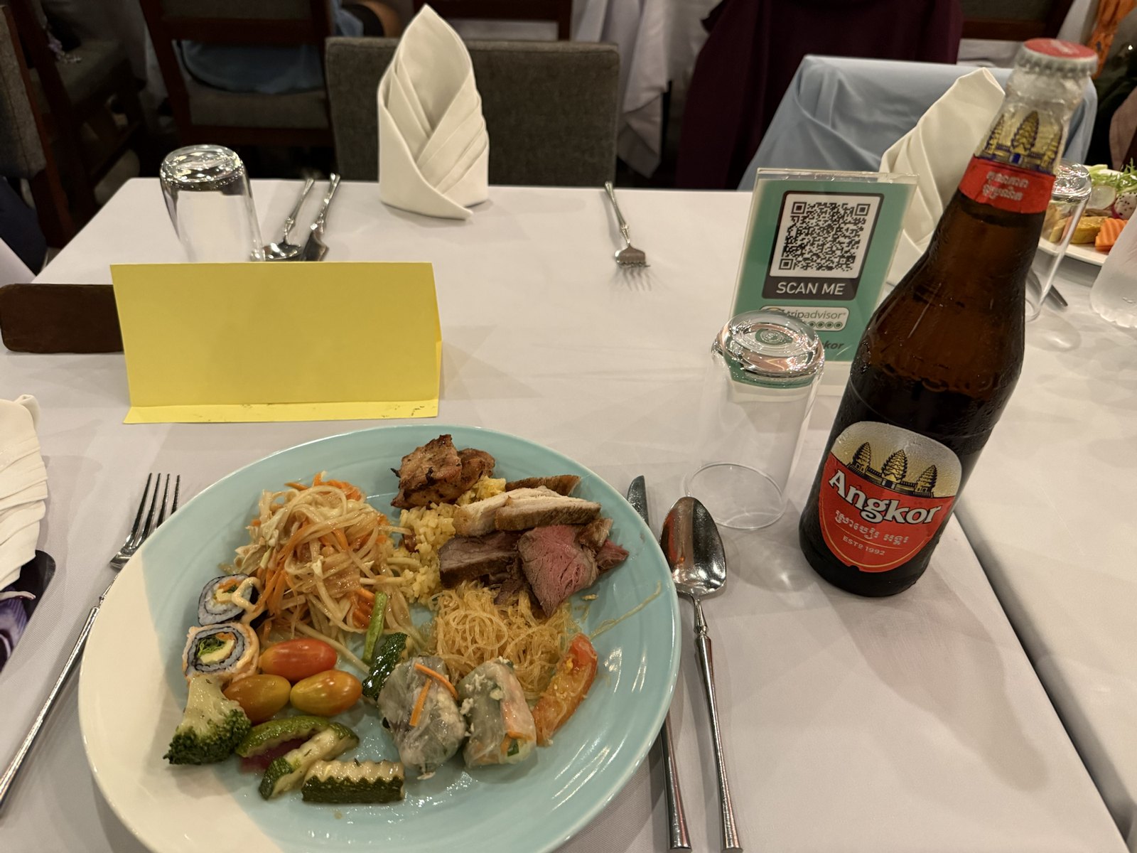 麺や肉料理や野菜や巻き寿司を盛り付けた夕食とアンコールビール
