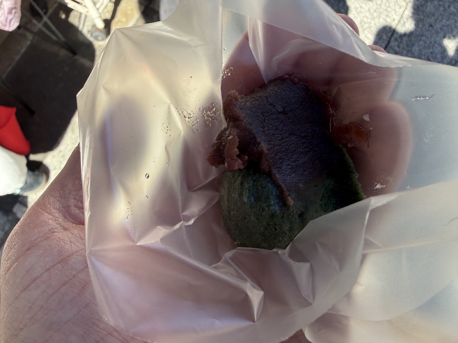 紙に包まれた濃い緑色の草だんごと粒あん