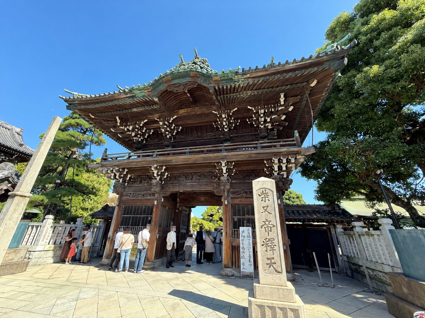 青空の下に建つ柴又帝釈天入口の二天門と石柱